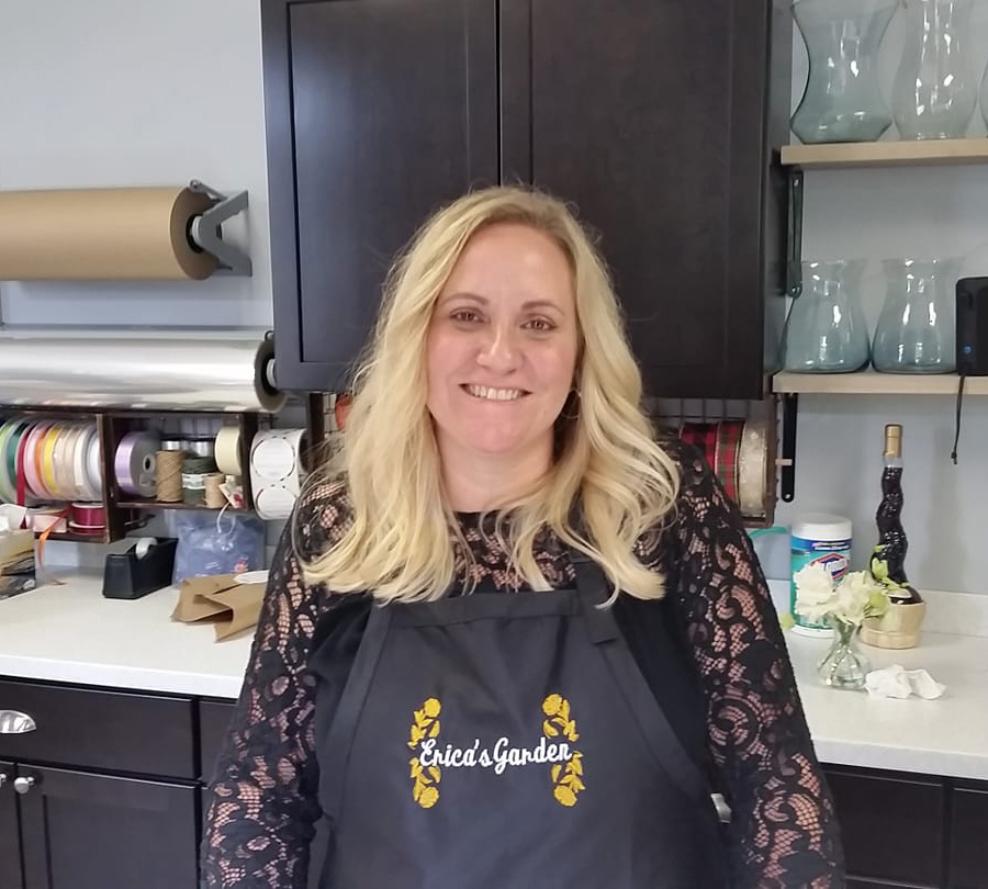 Erica smiling in a pretty lace top with an Erica's Garden apron on