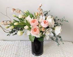 A lovely asymmetrical arrangement featuring garden roses, tulips, orchids and eucalyptus
