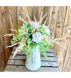 A luminescent cluster of pink and green florals spraying out the top of a pitcher
